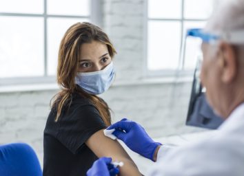 Young woman taking a vaccine from her doctor.