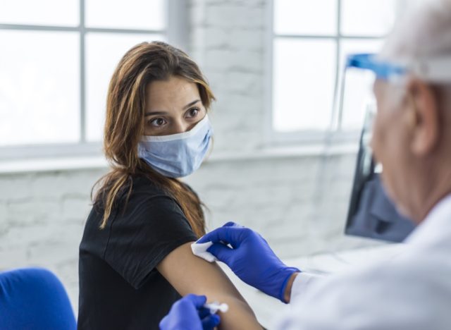 Young woman taking a vaccine from her doctor.