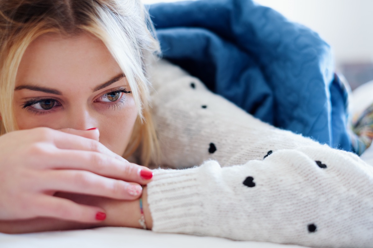 Sad woman lying on bed in a bedroom.