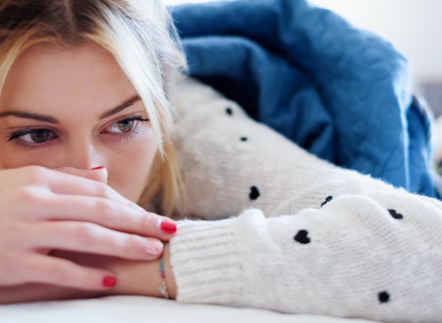 Sad woman lying on bed in a bedroom.