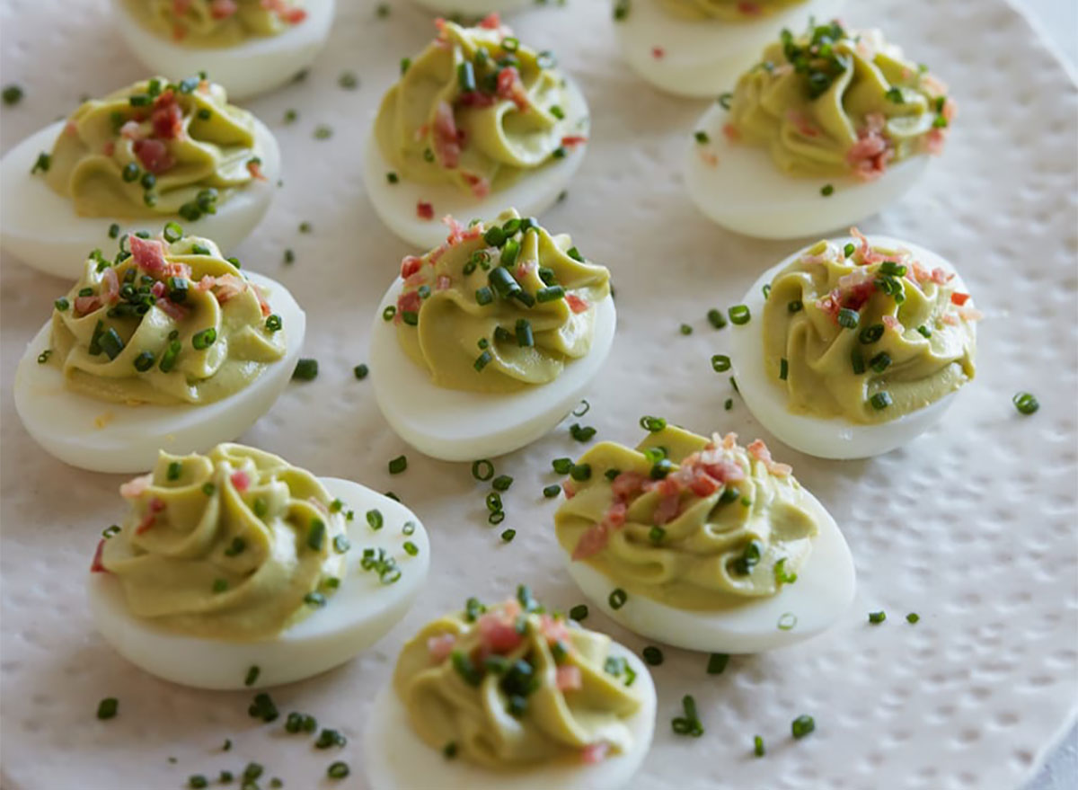 deviled eggs topped with chives and avocado mixture