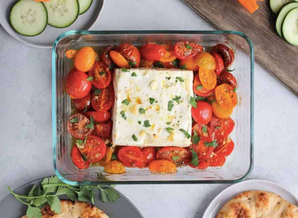 block of feta cheese in glass baking dish with tomatoes