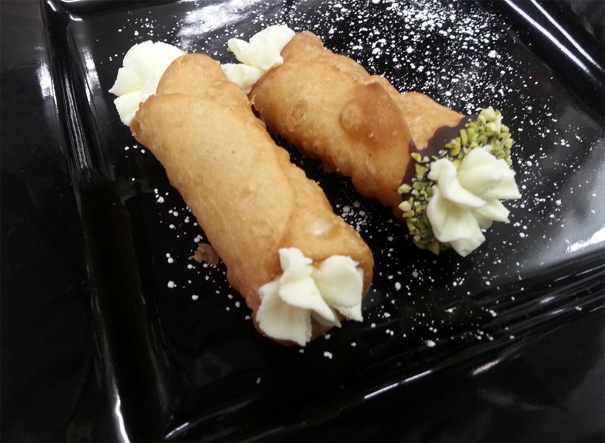 two cannolis on a black plate