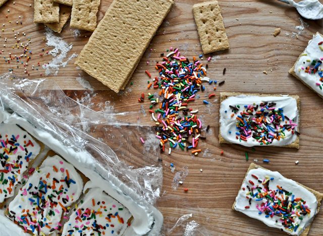 graham crackers topped with vanilla frosting and rainbow sprinkles