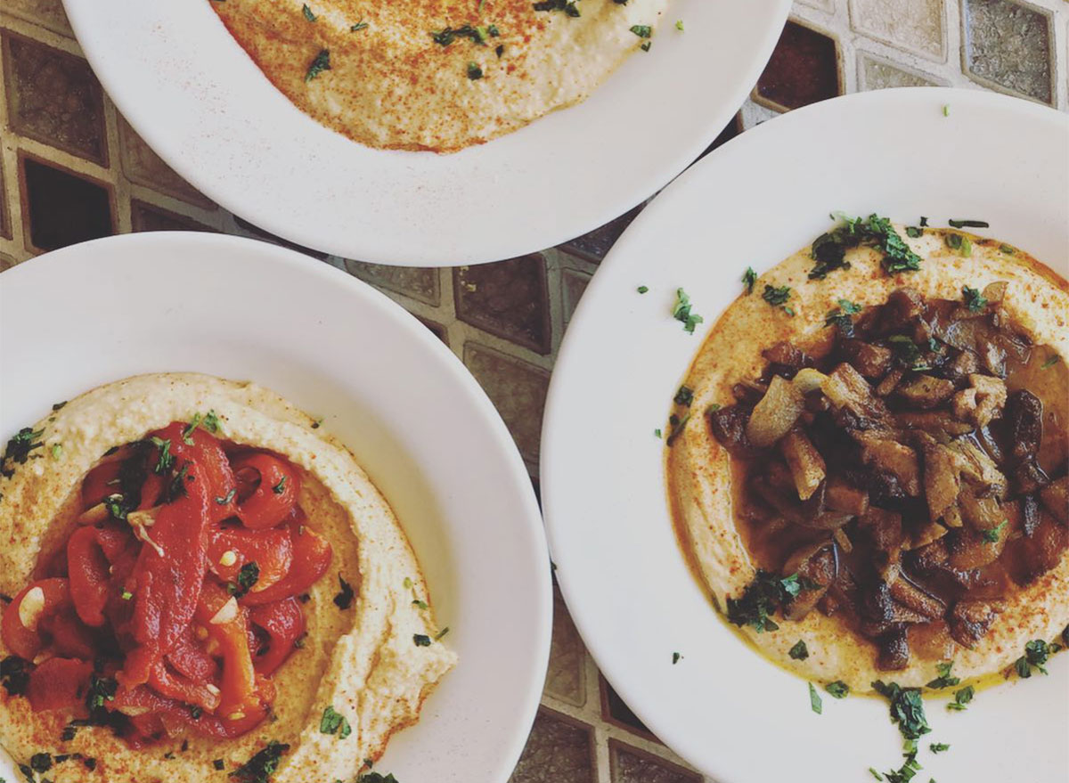 plates of hummus topped with caramelized onions and tomatoes