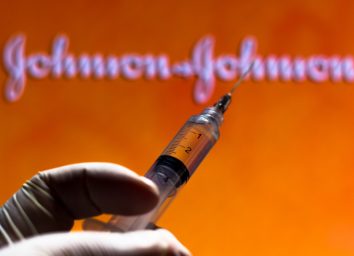 The medical syringe with Johnson and Johnson company logo displayed on a screen.