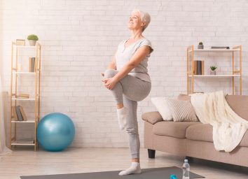 older woman balancing workout in living room
