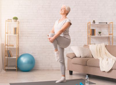 older woman balancing workout in living room