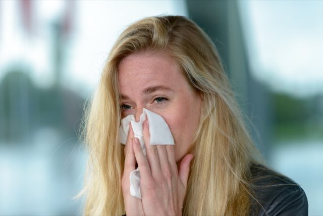 Woman blowing her nose into tissue