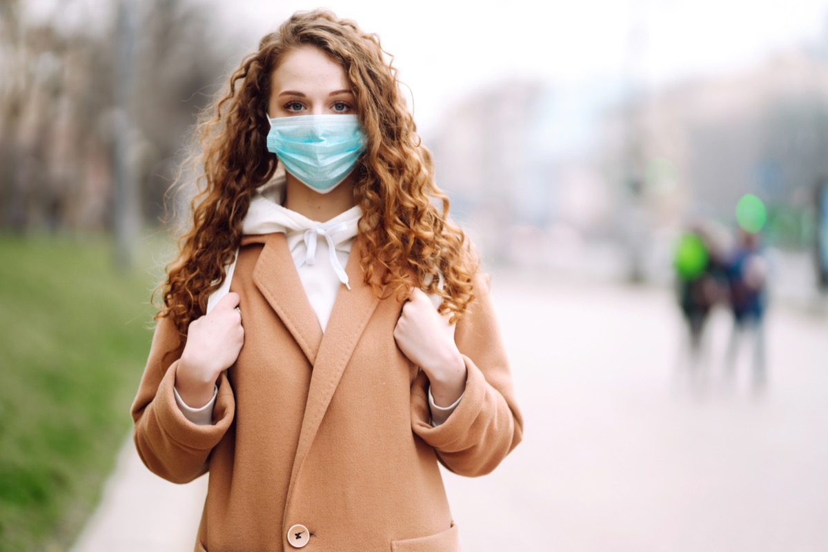 Woman wearing face mask standing on a street.