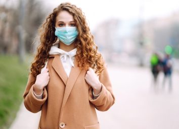 Woman wearing face mask standing on a street.