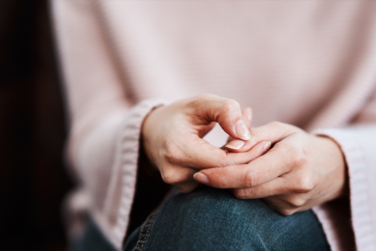 Woman sitting on a sofa and rubbing her hands.