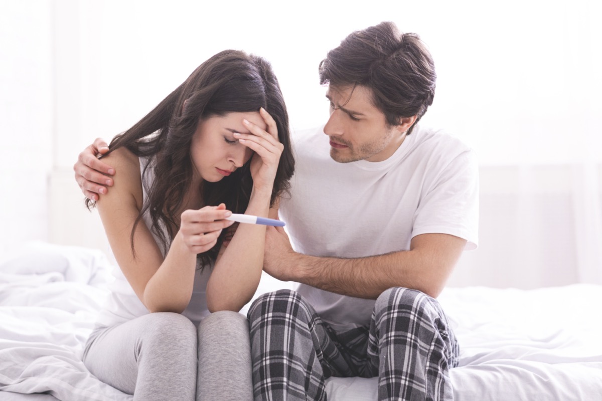 Hombre consolando a su esposa deprimida con prueba de embarazo negativa