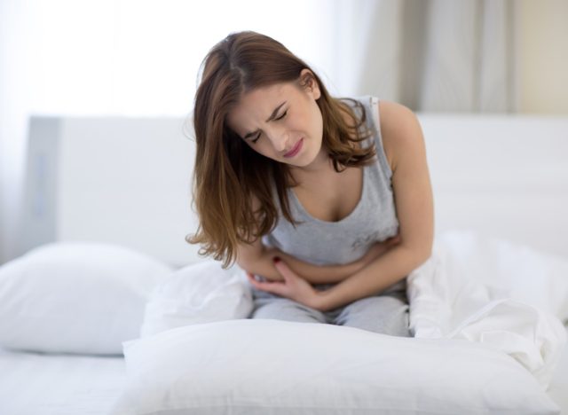 Woman sitting on the bed with pain.