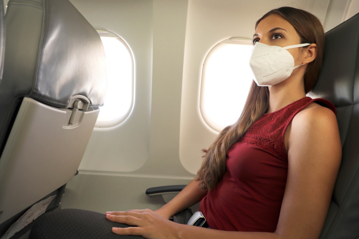 woman sitting inside airplane wearing KN95 FFP2 protective mask