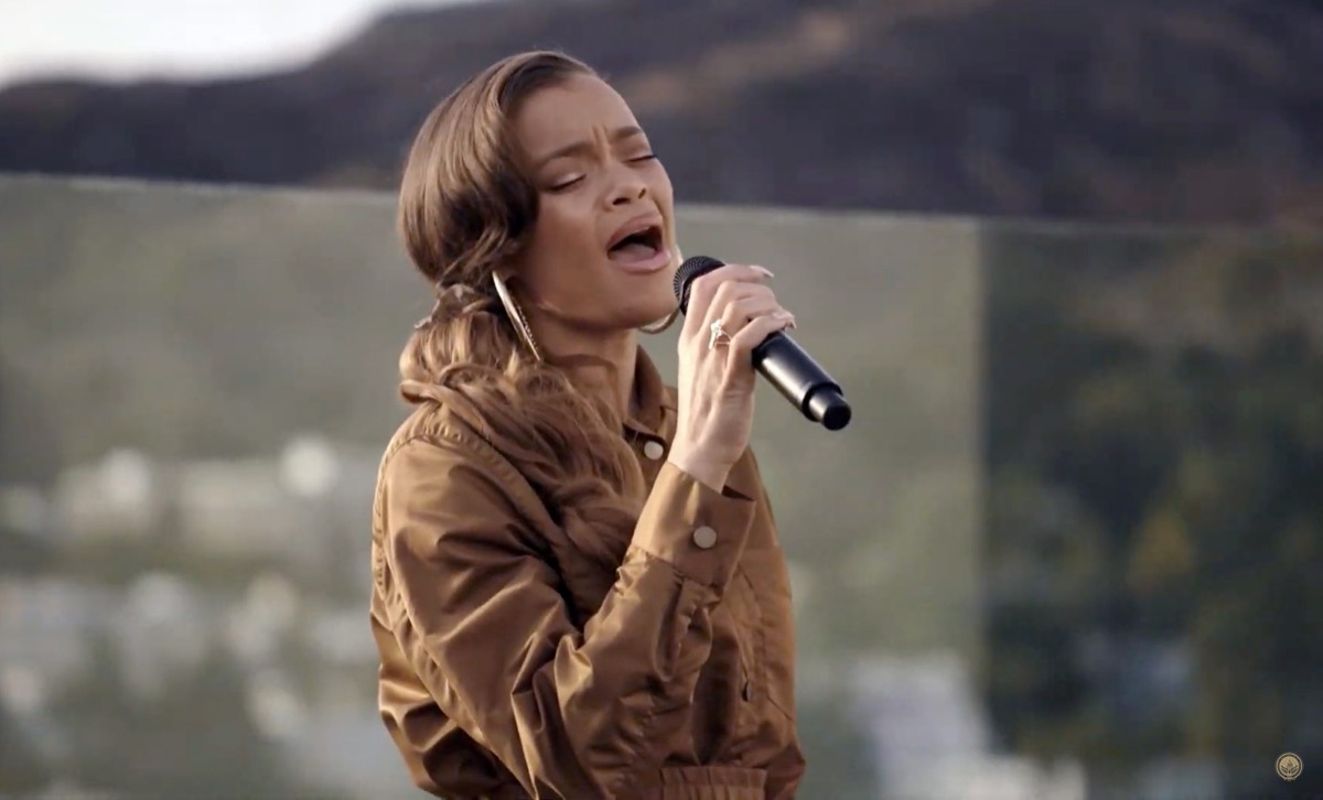 andra day in brown dress singing into microphne