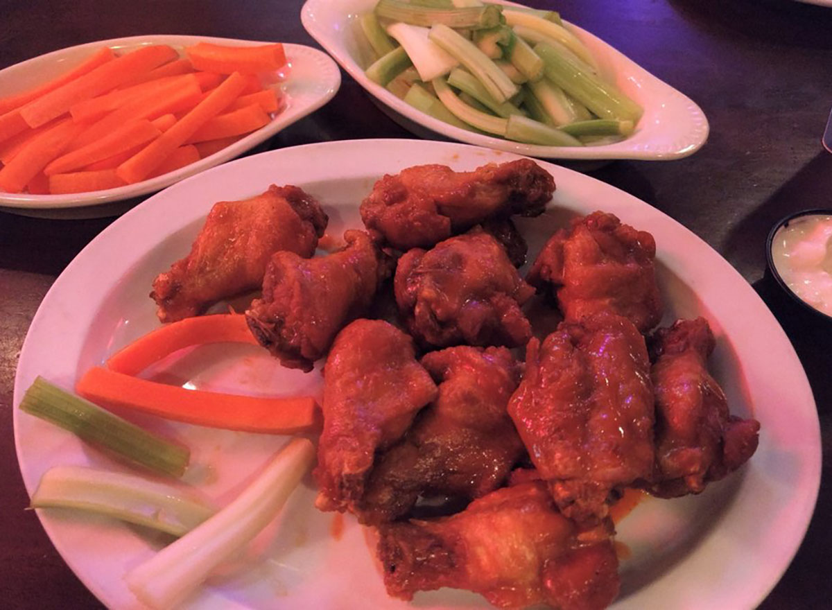 plate of buffalo wings with celery and carrot sticks
