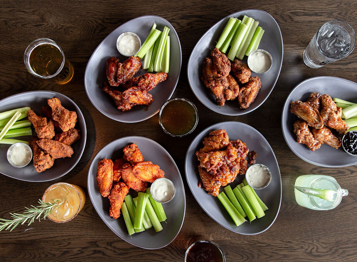 plates of spicy and regular chicken wings with celery slices and bleu cheese dip