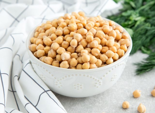 cooked chickpeas in a bowl with a dish towel and dill in the background