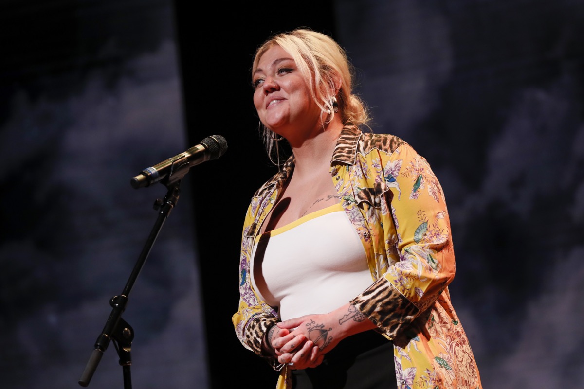 elle king in white tank top and yellow shirt on stage