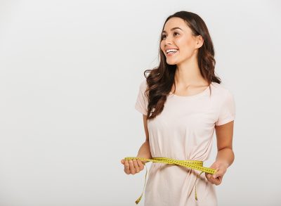 woman smiling measuring waistline