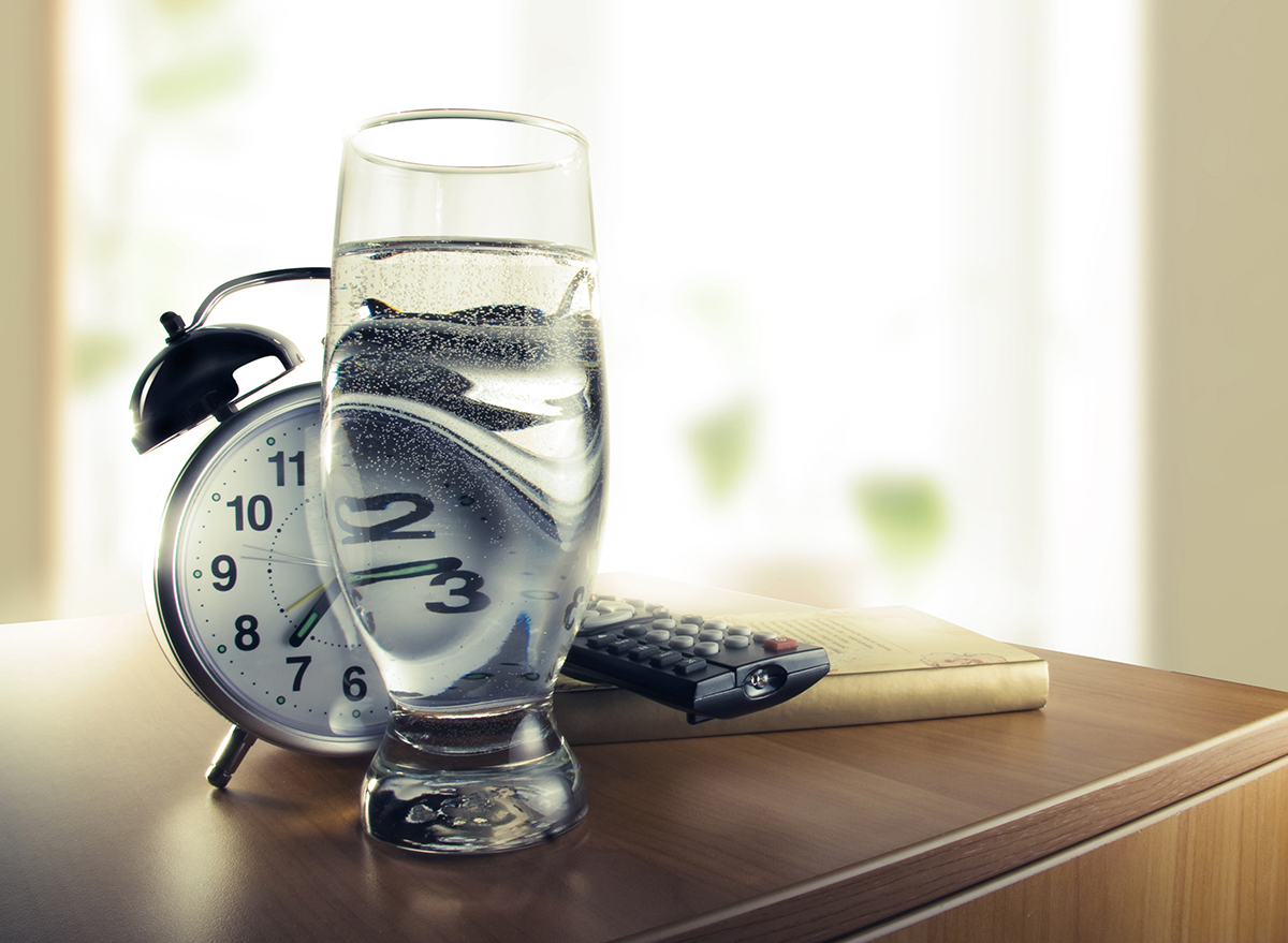 glass of water on nightstand next to alarm clock
