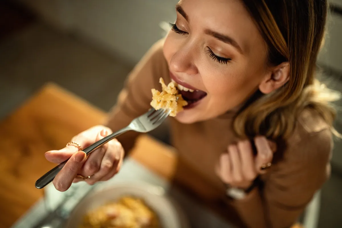 happy woman eating pasta for dinner