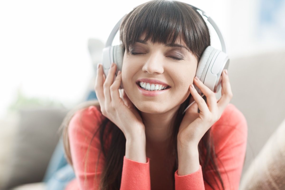 Young smiling woman relaxing and listening to music with headphones