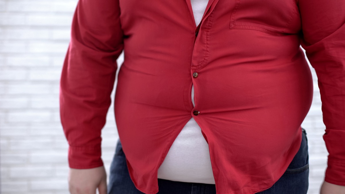 Obese man wearing tight red shirt, oversize clothing problem, insecurities