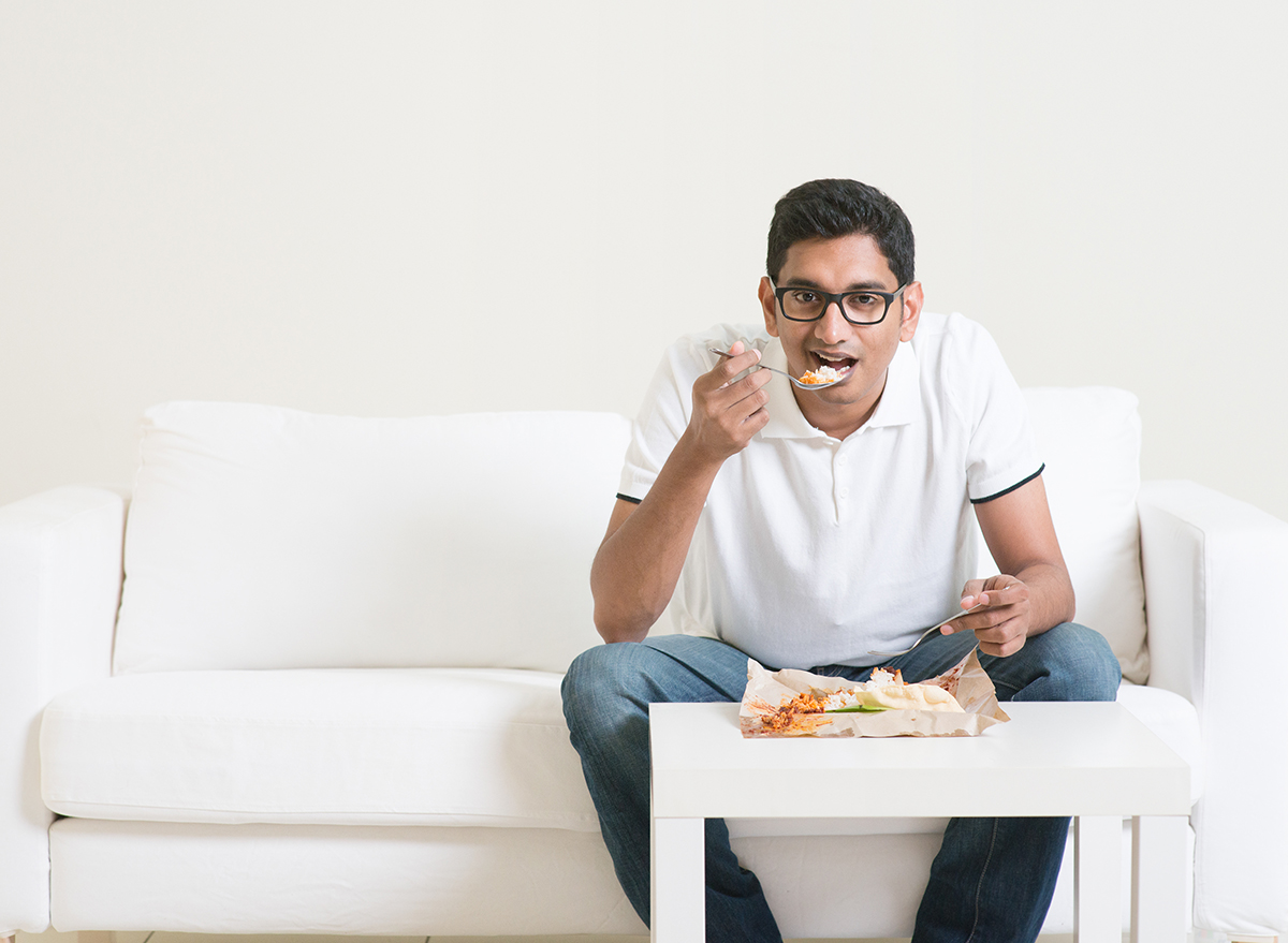 man eating dinner sitting on white couch