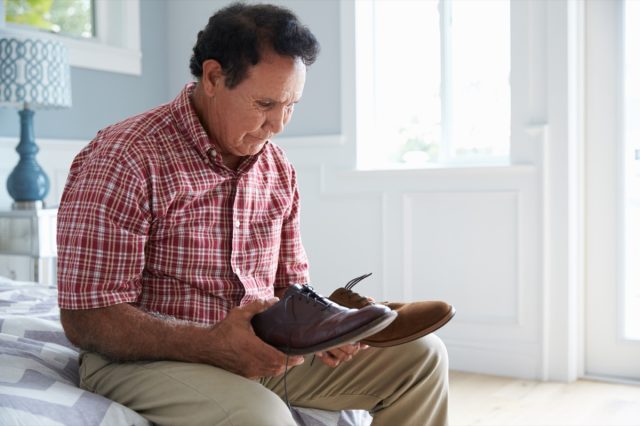 Senior Hispanic Man Suffering With Dementia Trying To Dress