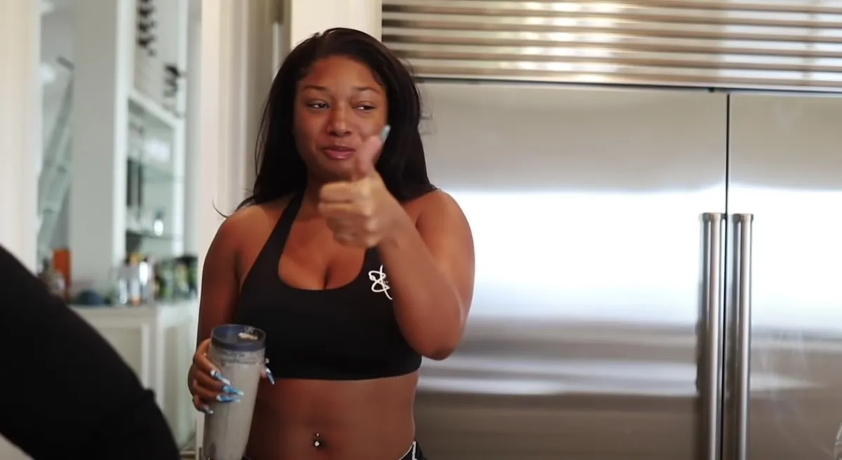 megan thee stallion in exercise gear holding a smoothie and giving a thumbs up