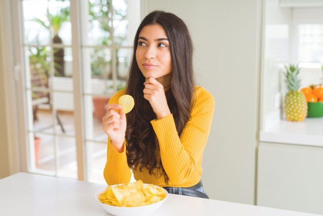 woman thinking about eating a potato chip and practicing mindful eating