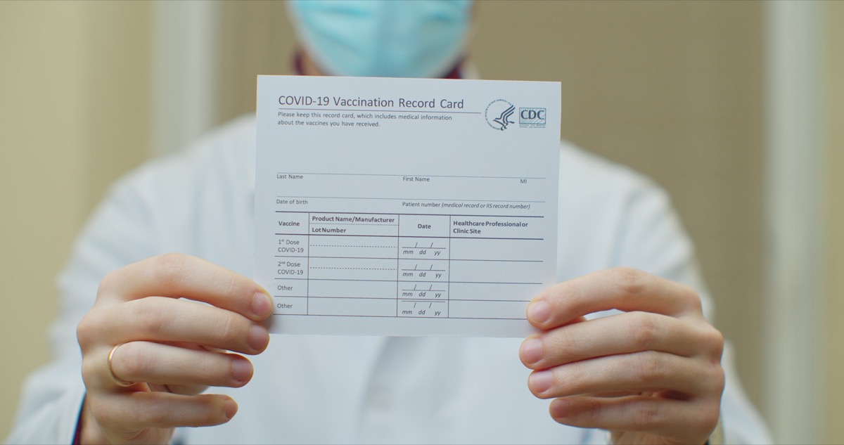 Doctor is holding a vaccination record card