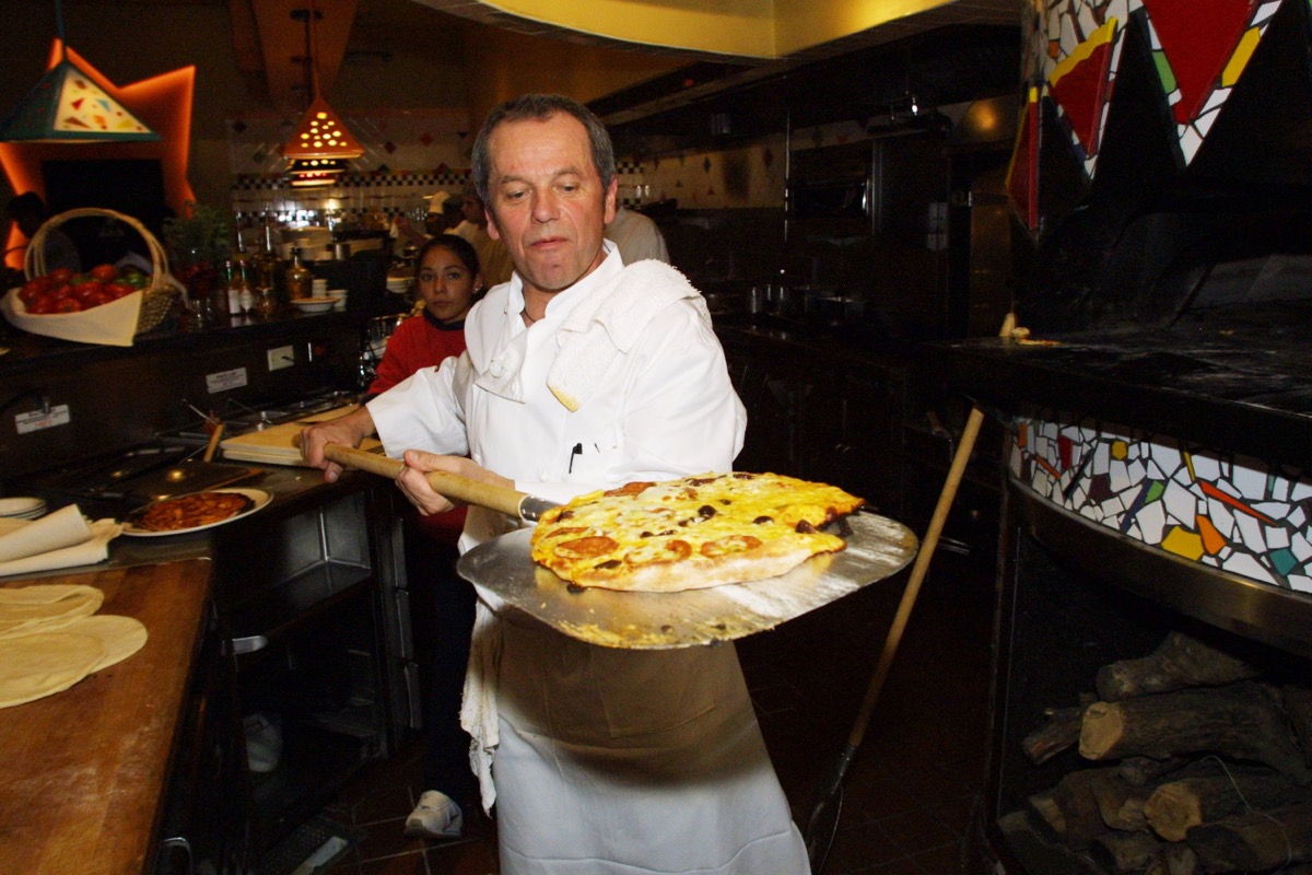 wolfgang puck holding pizza on paddle