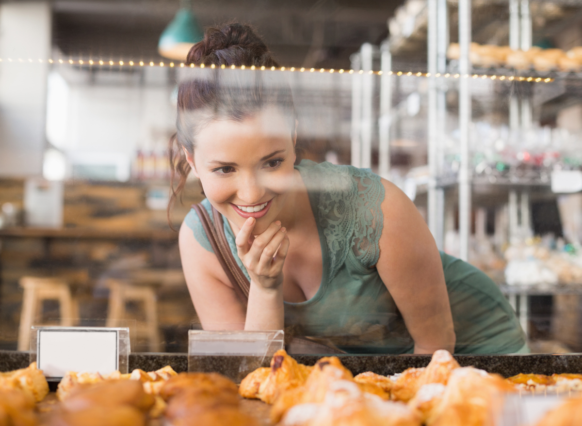 woman looking at unhealthy breakfast in pastry case