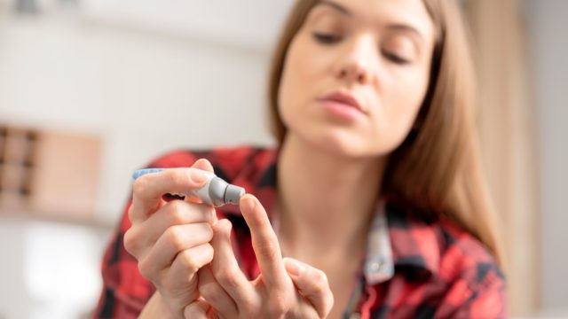 Young woman measures blood sugar level.