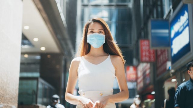 Woman with protective face mask commuting in downtown city street to protect and prevent from the spread of viruses in the city