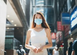 Woman with protective face mask commuting in downtown city street to protect and prevent from the spread of viruses in the city