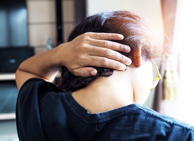 Woman use hand to massage back of neck to relax head muscles and relieve pain.