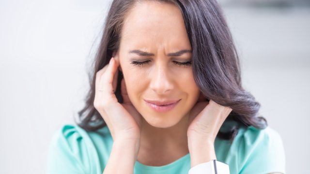 Young woman have headache migraine stress or tinnitus