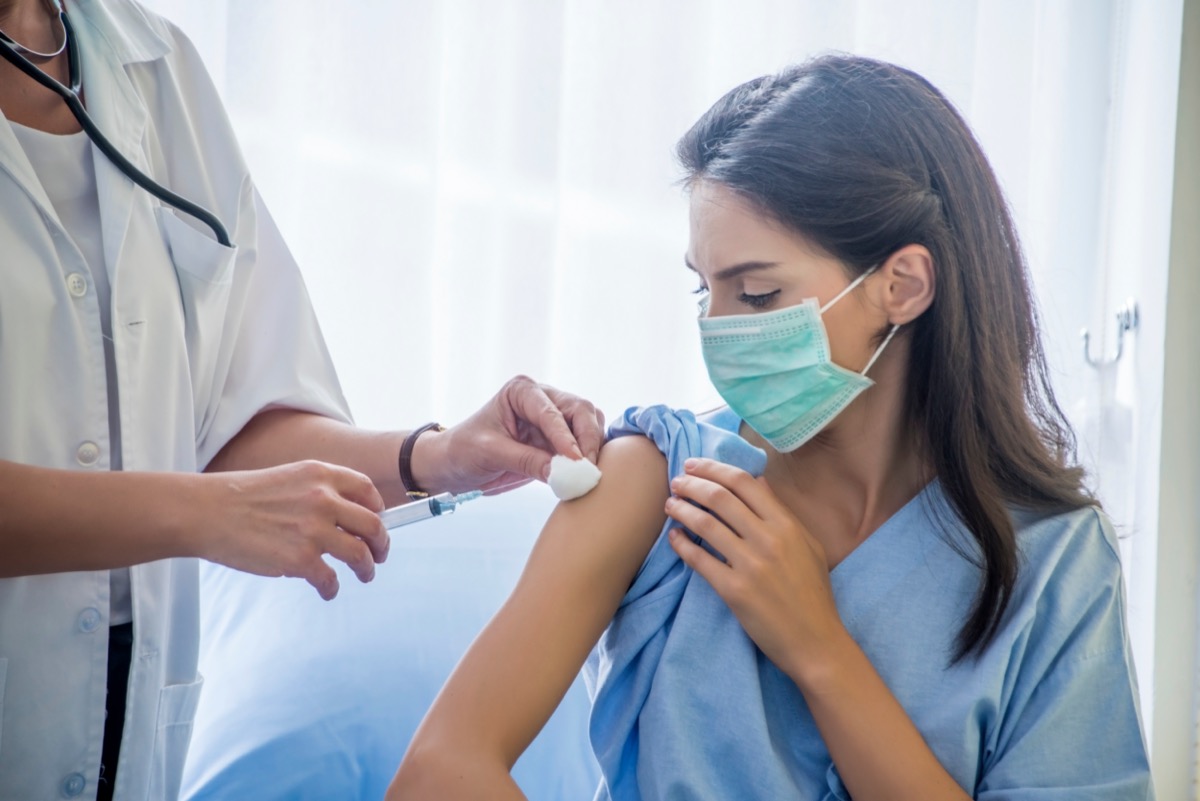 The female doctor syringe injection to the young patient put on a mask in the hospital