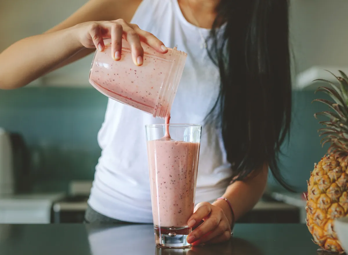 woman pouring a smoothie into a glass