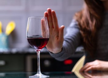 woman turning down glass of red wine