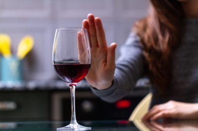 woman turning down glass of red wine