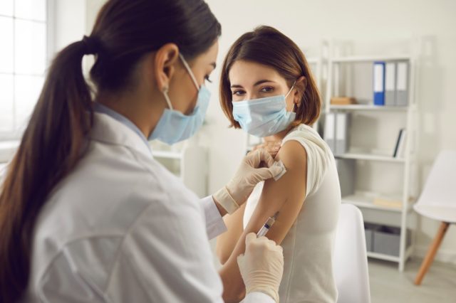 Woman in medical face mask getting Covid-19 vaccine at the hospital