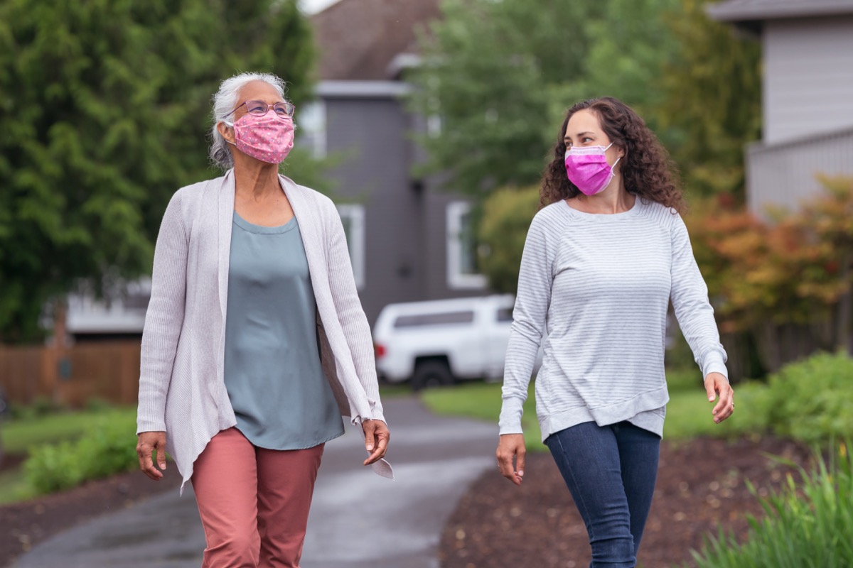 Two women wearing face masks are enjoying the outdoors during a coronavirus