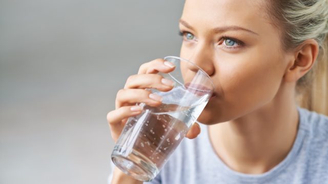 Woman drinking water from glass.