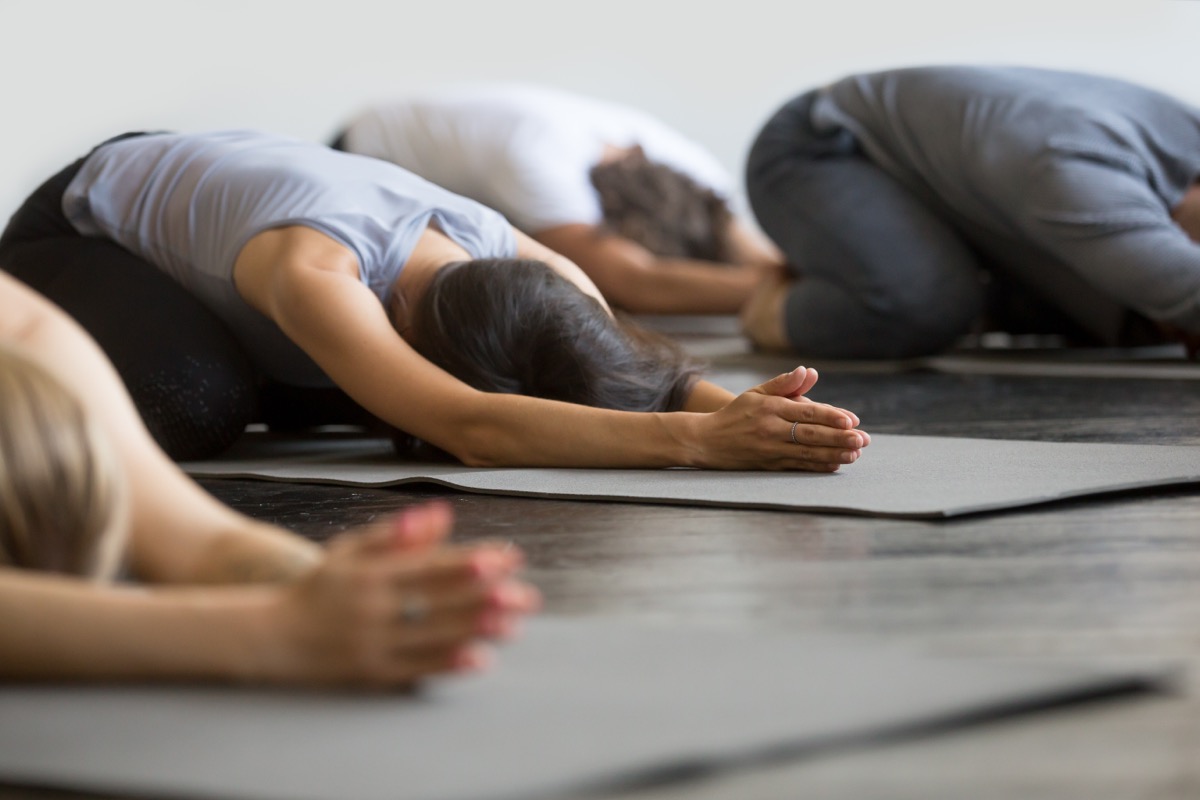 women in child's pose on yoga mat