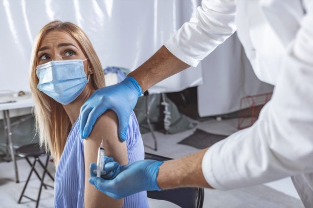 Doctor vaccinating female patient in clinic.